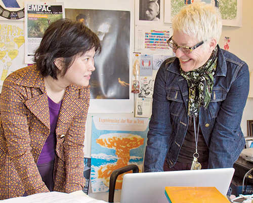 Two professors meeting and looking at a laptop