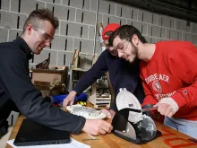 Three students work with a piece of equipment