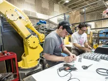Two students work in front of large equipment in the student run makerspace